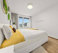 A bedroom in a 4-room apartment with a bed, yellow accessories, and a wooden decor floor.