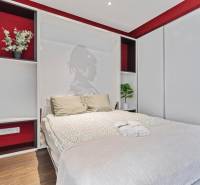 Bedroom with a decorative wall, bed, and storage space in a two-room apartment, floor with wooden decor.