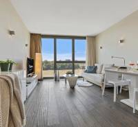 A stylish living room in a two-room apartment with a wooden decor floor and large windows.