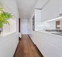A kitchen in a 2-room apartment with white cabinets and a wood-patterned floor.