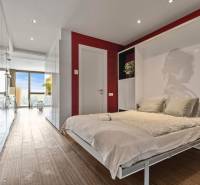 Bedroom with a bed, plants, and a wooden decor floor in a 2-room apartment.