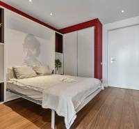 Bedroom in a 2-room apartment with wood-patterned flooring, red walls, built-in wardrobes.