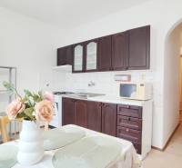 A kitchen in a 2-room apartment with dark cabinets and a dining table with decoration.