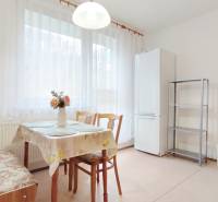 Kitchen in a 2-room apartment with a dining table, chairs, and a refrigerator.