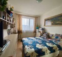 A bedroom with a bed, shelves, and a wooden decor floor in a 3-room apartment.