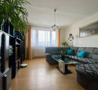 Living room with a large gray sofa, glass table, and wooden decor flooring.