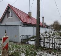 A family house in Tornyosnémeti with a red roof, a side fence, and a snow-covered garden.