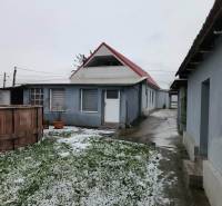 The snowy yard of a family house in Tornyosnémeti with a garden pool and a concrete walkway.