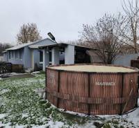 A snowy yard of a family house in Tornyosnémeti with a swimming pool and a wooden gazebo.