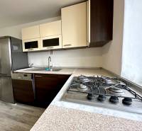 A kitchen in a 2-room apartment with a gas stove and a floor with a wood decor.