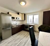 A kitchen in a 2-room apartment with a wooden decor floor and a table with chairs.