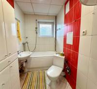 Bathroom in a 2-room apartment with a bathtub, sink, and white tiles.