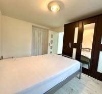 Bedroom in a two-room apartment with a bed, wardrobe, and floor with a wooden decor.