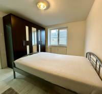 Bedroom with a large wardrobe and bed in a 2-room apartment, light floor with wood decor.