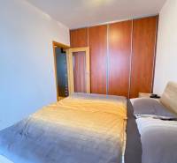 A bedroom in a two-room apartment with a built-in wardrobe and a bed with a wooden decor.