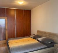 Bedroom in a two-room apartment with a bed and a wardrobe, floor with wooden decor.