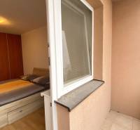 Bedroom in a two-room apartment with a bed, wooden decor flooring, and access to the terrace.