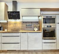 A kitchen unit in a studio apartment with a wooden decor, appliances, and lighting.