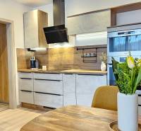 A kitchen in a studio apartment with wooden floor decor and modern equipment.