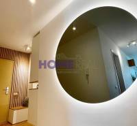 Interior of a 3-room apartment with a wooden decor floor and a round mirror on the wall.
