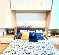 Bedroom in a 3-room apartment with a wooden decor floor and floral bedding.