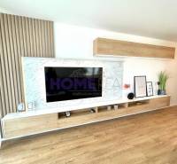 Living room wall unit with a television and a floor with a wooden decor in a 3-room apartment.