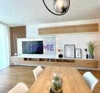 A bright living room in a 3-room apartment with a wooden decor floor and modern linear lighting.