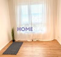 A room with a wooden floor decor and white curtains in a 3-room apartment.