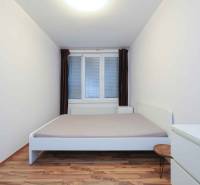 Bedroom in a 2-room apartment with white furniture and a wooden decor floor.