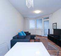 Living room of a 2-room apartment with a couch, television, and floor with a wooden decor.