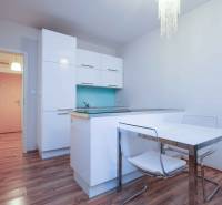 A kitchen in a 2-room apartment with white cabinets and a wooden decor floor.
