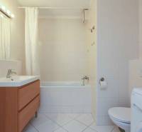 Bathroom with a bathtub, sink, cabinet, toilet, and washing machine in a 2-room apartment.