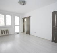 A bright room in a 3-room apartment with wood-patterned flooring and large windows.