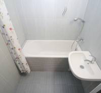 Bathroom with a bathtub and a sink in a 3-room apartment with tiles.