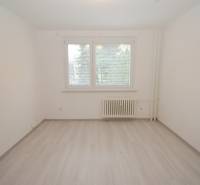 A room with white paint, a window with blinds, and a floor with wood decor in a 3-room apartment.