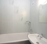 Bathroom in a 3-room apartment with a bathtub, sink, and mirror, light tiles.