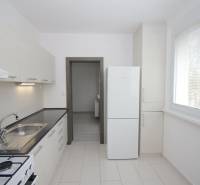 A kitchen with a white unit in a 3-room apartment, large window, refrigerator.