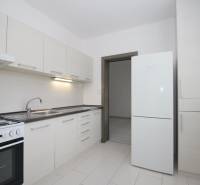 A kitchen in a 3-room apartment with white cabinets and a white floor.