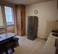 Kitchen in a 3-room apartment with a dining table and a refrigerator, tiled floor.