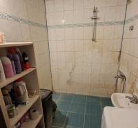 Cozy bathroom with a washing machine, white tiles, and shelves, ideal for a 3-room apartment.