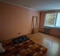 A room in a 3-room apartment with a wooden decor floor, simple furnishings.