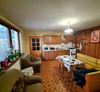 A kitchen in a family house with wooden decor, a sofa set, and a dining table.
