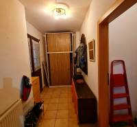 A hallway in a family house with tiles, a shoe cabinet, a coat rack, and a wardrobe.