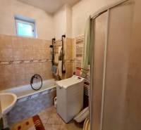 Bathroom with a bathtub, shower, and washing machine in a family house.