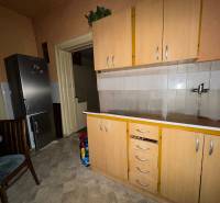 A kitchen in a family house with a refrigerator, cabinets, and a tiled floor.