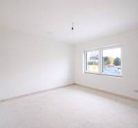 An empty room with white walls and a large window in a family house.