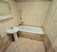 A bathroom in a 3-room apartment with a bathtub, a sink, and beige ceramic tiles.