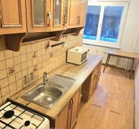 A kitchen with a wooden decor floor and a window, part of a 3-room apartment.