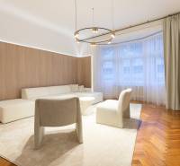 Living room in a three-room apartment with a wooden decor floor, beige carpet, and seating.