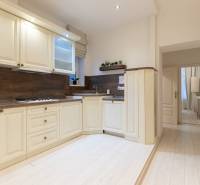 A kitchen in a 3-room apartment with a wood-patterned floor and light-colored furniture.